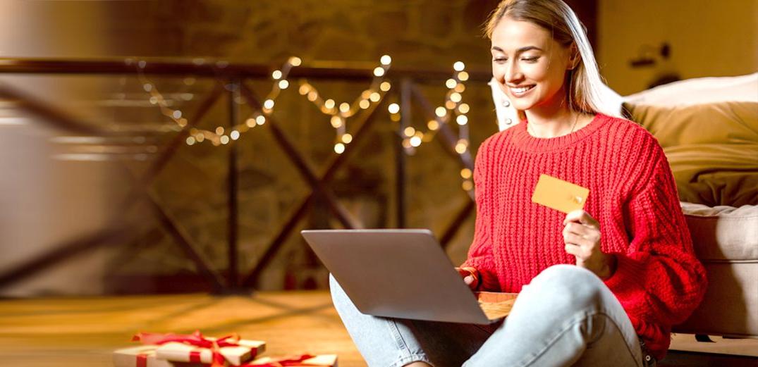 A woman uses her bank card for holiday shopping on her laptop.