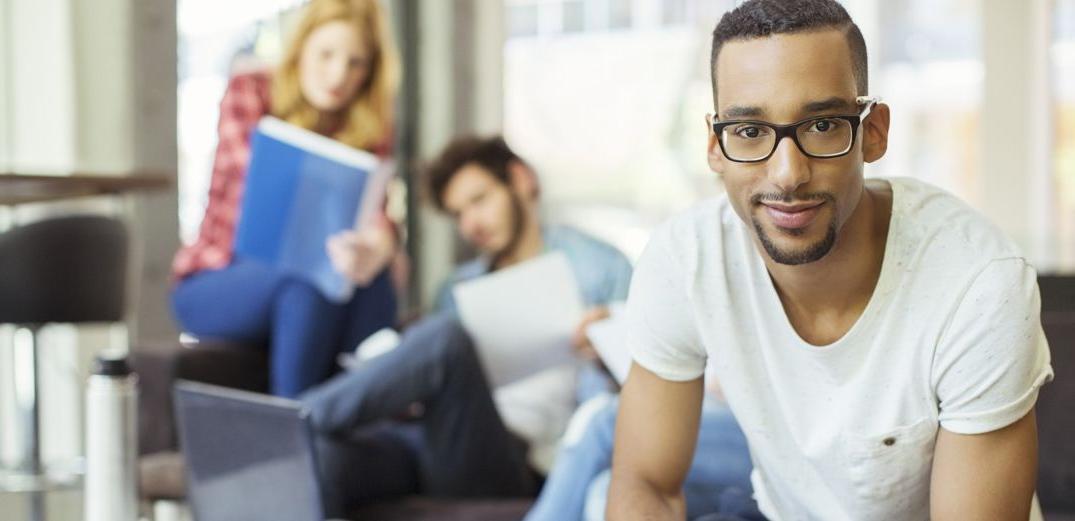 A Gen Z Patelco member looks at the camera as friends gather behind him.