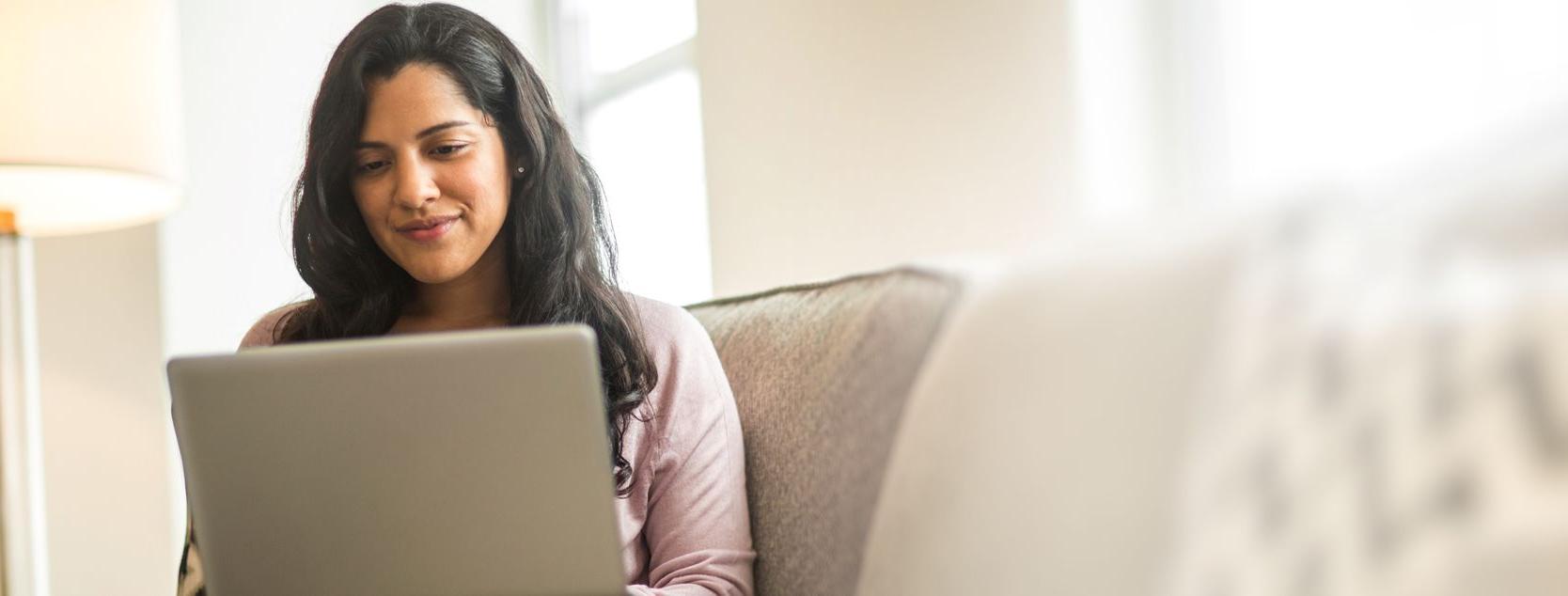 A brown-haired woman reviews her Patelco Online banking statement.