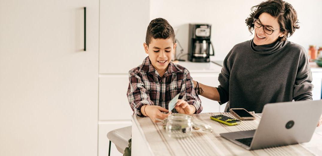 A smiling mom pats her son on the back while they talk about budgeting and savings.